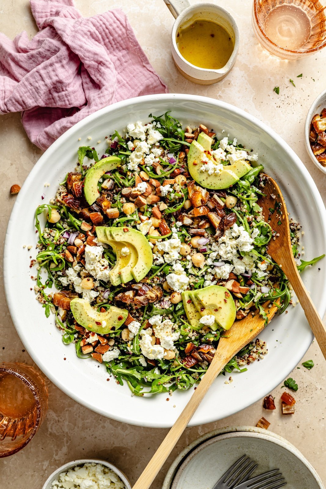 chickpea arugula quinoa salad with avocado in a bowl with wooden spoons