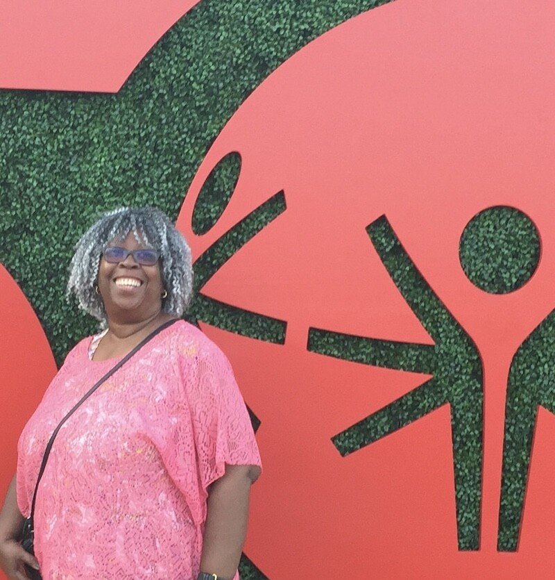 woman in a pink shirt smiling behind the special olympics logo