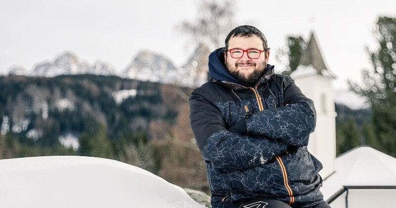 Man wearing winter clothes posing for the camera with snowy landscape in the background