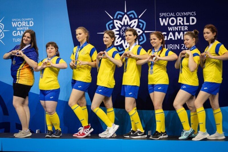 A Ukrainian floorball women's team poses with their medals after winning at the Special Olympics Winter Games. The women all make hearts with their hands