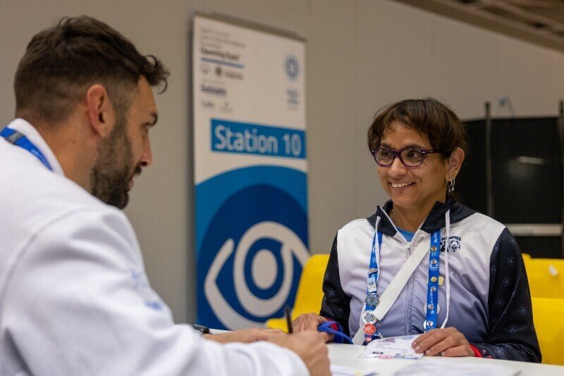 A female athlete sitting and talking to a healthy athletes representative.